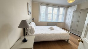Une chambre à coucher bien rangée, avec un lit, des lampes de chevet, un radiateur et une armoire.