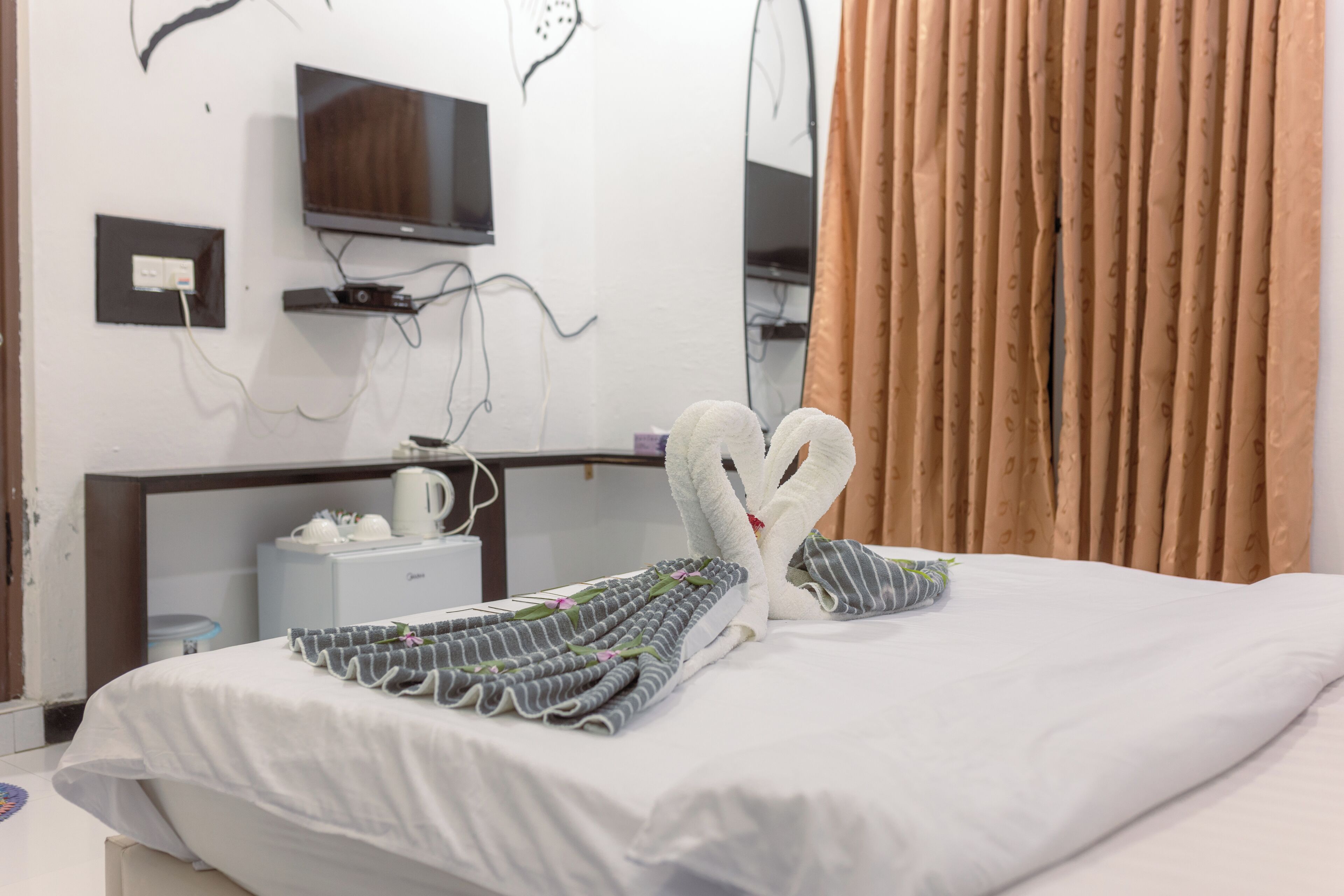 A hotel room with a bed, a television mounted on the wall, and a mirror.