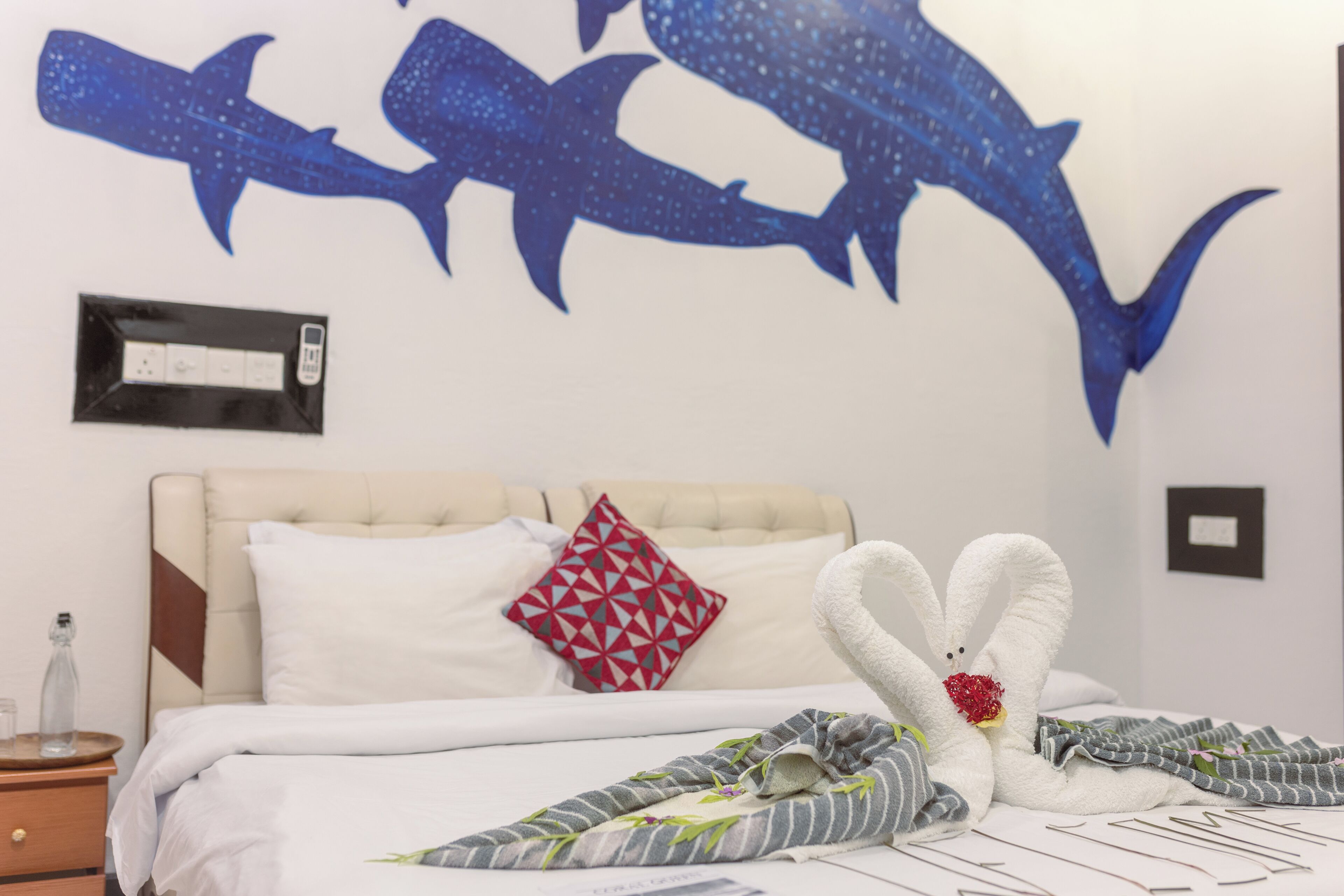 Una camera d'albergo con un letto, una cornice appesa al muro e una decorazione a tema squali.