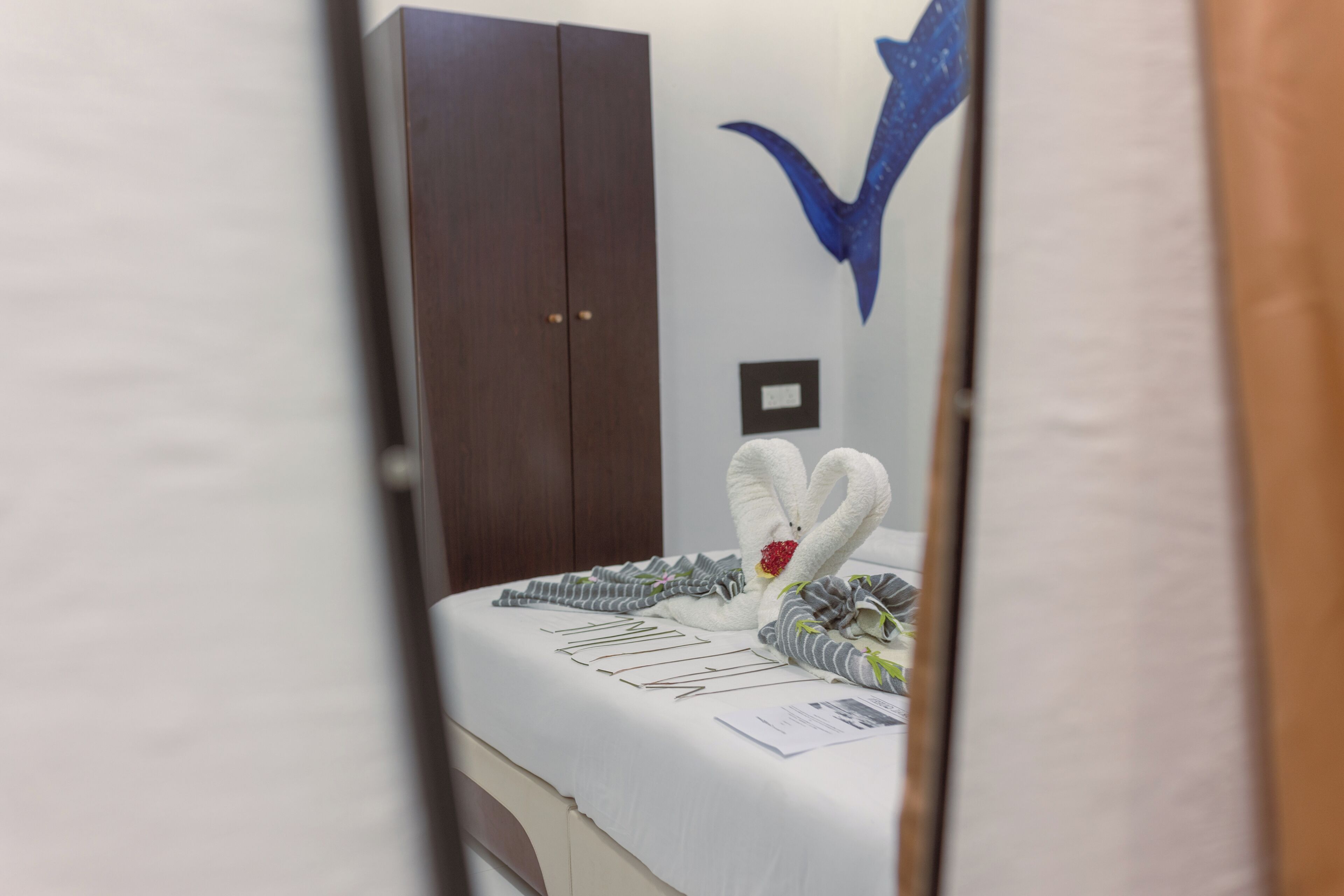 A hotel room with a bed, a wardrobe, and a wall-mounted light switch.