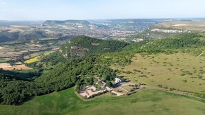 A rural landscape with a white building surrounded by green fields and hills. - Across from the Millau Viaduct: 1-bedroom / renovated sheep barn (Creissels)