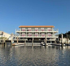 Un edifici amb diversos pisos davant del mar, amb balcons i una zona de moll.