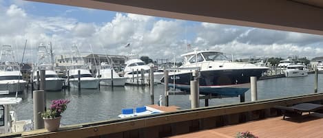 A marina with boats docked, a wooden deck with potted plants, and a clear sky.
