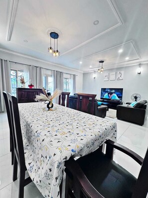 A modern living room with a dining area, featuring a large TV, comfortable seating, and decorative elements. - Apartments - Furnished Condos - Yassa Douala - WILMA HOUSE: Just Like Home (Yassa)