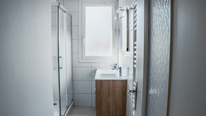 A modern bathroom with a glass shower, a wooden vanity, and a large mirror. - 38 m² apartment with balcony in Montpellier (Montpellier)