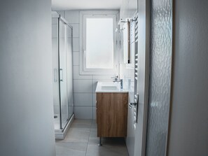 A modern bathroom with a glass shower, a wooden vanity, and a large mirror. - 38 m² apartment with balcony in Montpellier (Montpellier)
