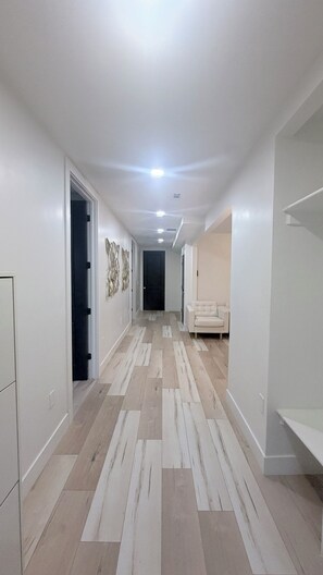 A hallway with a light-colored floor, white walls, and a door at the end. - Ultimate 9BR/9BA Luxury Retreat @ SLC Central & Loaded (West Valley City)