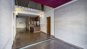Un pasillo con una recepción, una puerta de madera y una escalera que sube a un nivel superior.