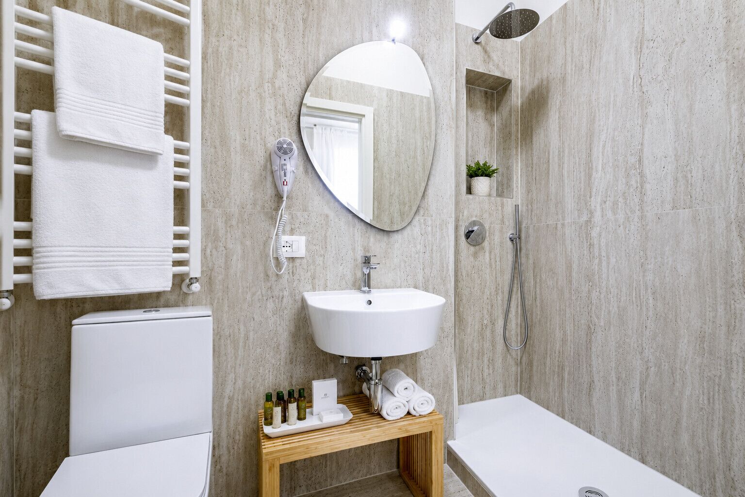 Ein modernes Badezimmer mit Waschbecken, Spiegel, Duschbrause und Toilette.