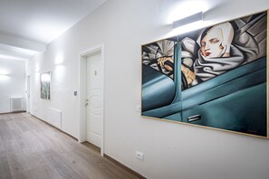 Een hal met een groot abstract schilderij aan de muur, een witte deur en een radiator.
