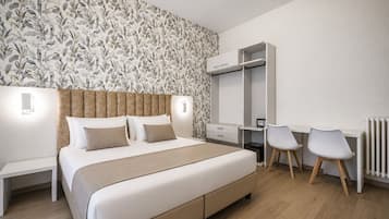 A bedroom with a bed, bedside tables, a desk with chairs, and a wardrobe.