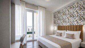 Habitación de hotel con una cama grande, un escritorio y vistas al exterior a través de una puerta corrediza.
