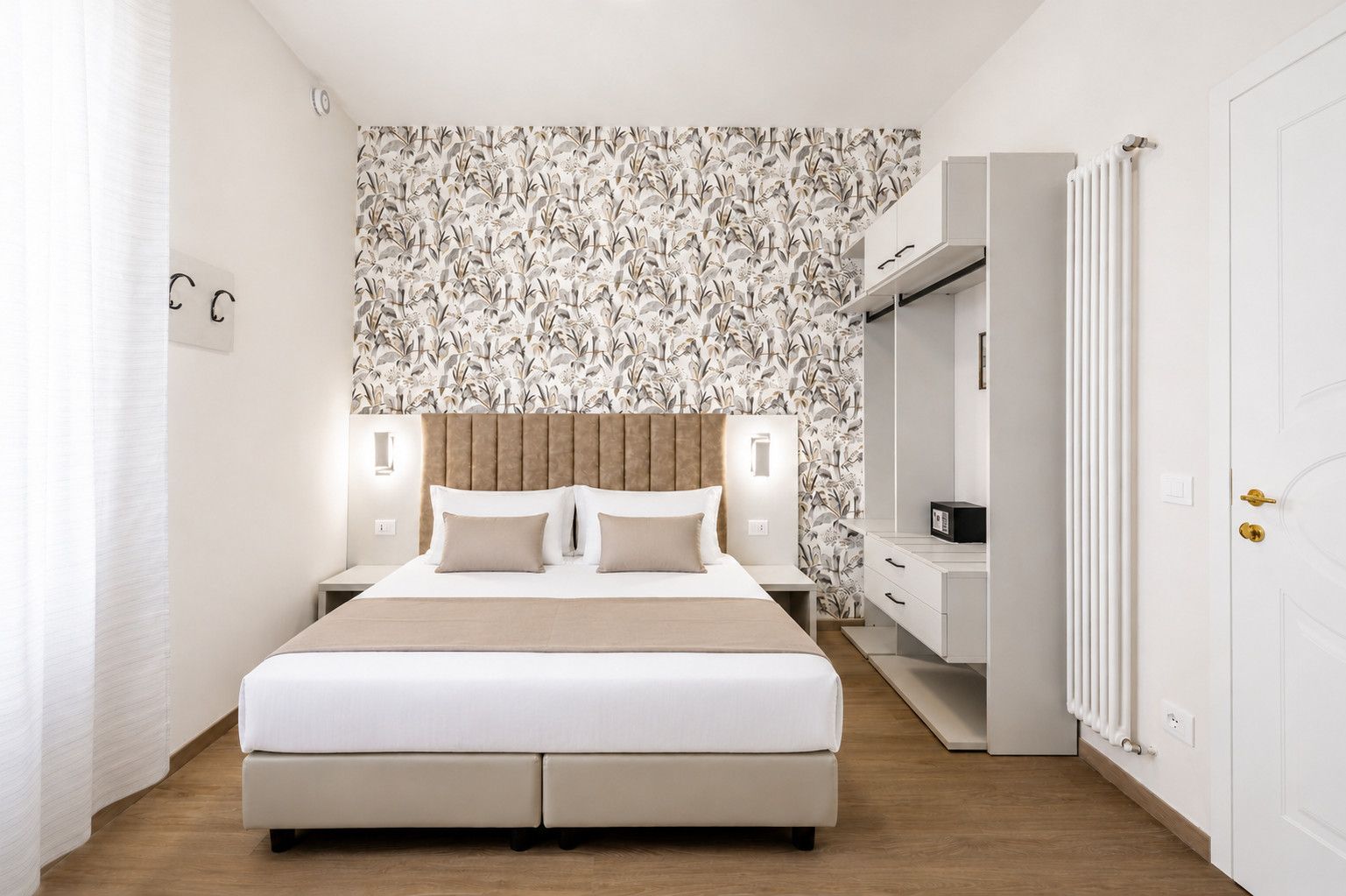 A modern bedroom with a large bed, a headboard, bedside tables, a wardrobe, and a radiator.