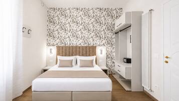 A modern bedroom with a large bed, a headboard, bedside tables, a wardrobe, and a radiator.