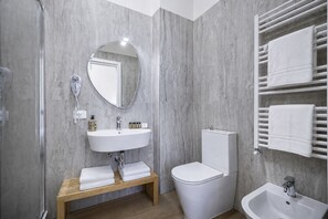 Une salle de bain moderne avec un lavabo blanc, un miroir rond et des toilettes.