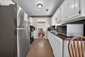 A kitchen with a refrigerator, stove, microwave, and wooden chair. - Quiet & Cozy 3BR Home w/ Soaking Tub + Laundry (Columbus)