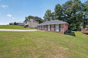 A residential property with a well-maintained lawn, a detached house with a brick facade, and a covered porch. - Quiet & Cozy 3BR Home w/ Soaking Tub + Laundry (Columbus)