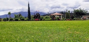 Un campo cubierto de hierba con un edificio de techo rojo y una montaña al fondo.
