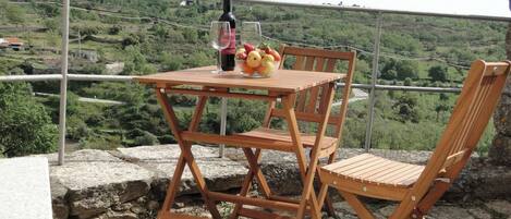 Un conjunto de mesa y silla de madera en un balcón con vistas a un paisaje verde.