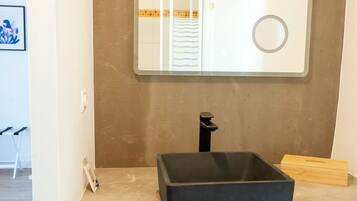 Une salle de bain avec un lavabo noir, un miroir et un porte-serviettes.