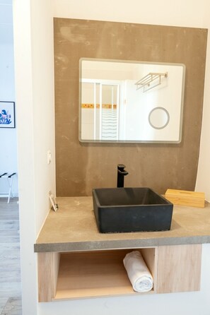 A bathroom with a black sink, a mirror, and a towel holder. - Vrbo Property (NIMES)