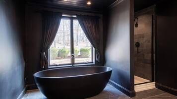 Une salle de bain moderne avec une baignoire sur pieds, un espace douche et une fenêtre avec des rideaux.
