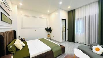 A modern bedroom with a bed, a sofa, a small table, and a potted plant.