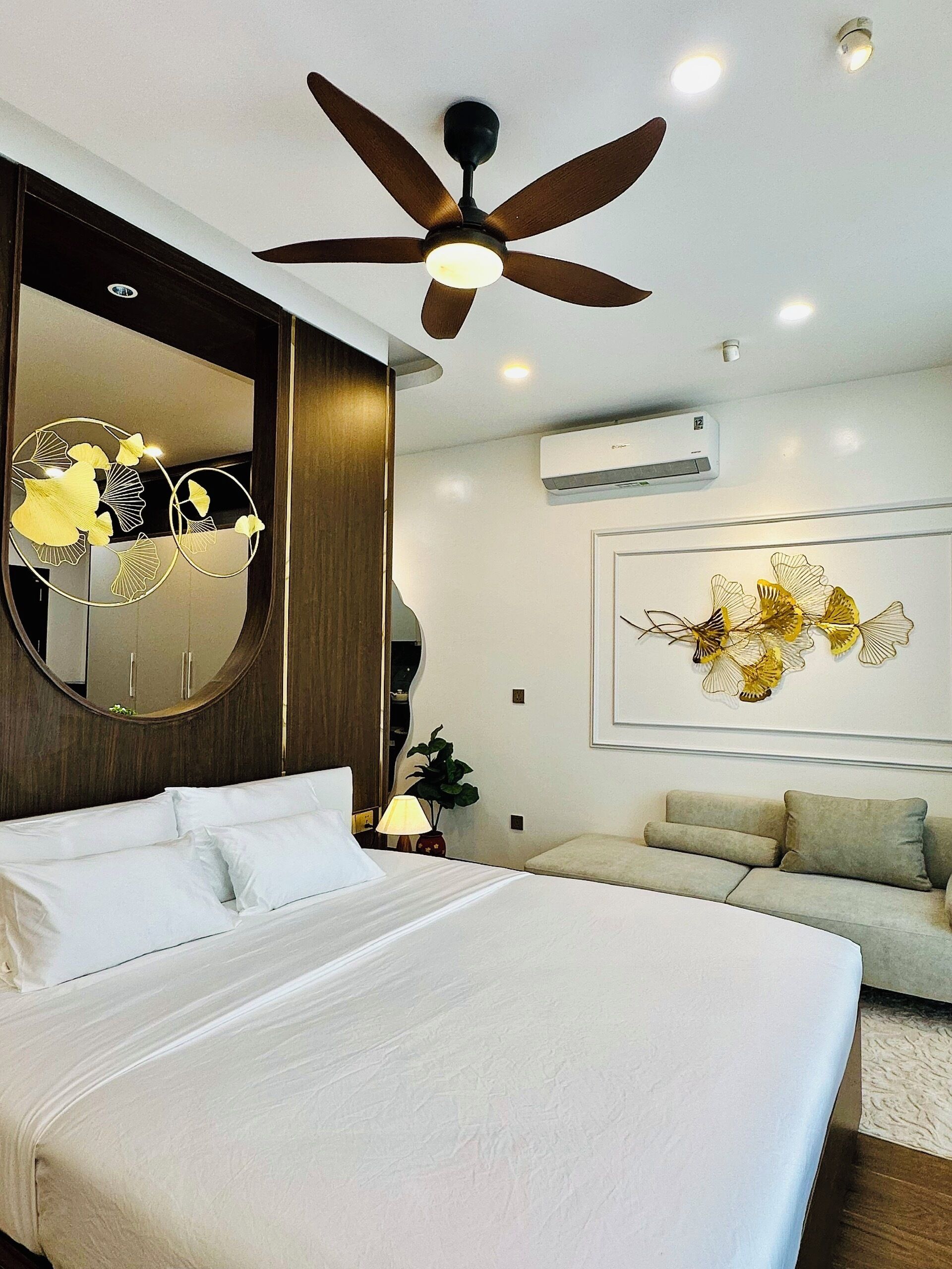 Een moderne hotelkamer met een groot bed, een plafondventilator, een airconditioning en decoratieve wandkunst.