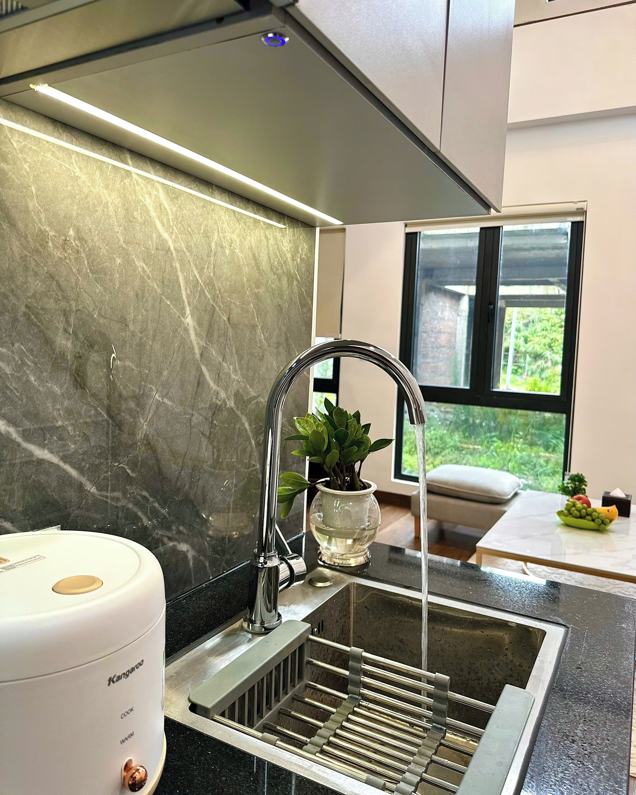 Una cocina moderna con un lavamanos de acero inoxidable, una cocina integrada y un protector contra salpicaduras de mármol.