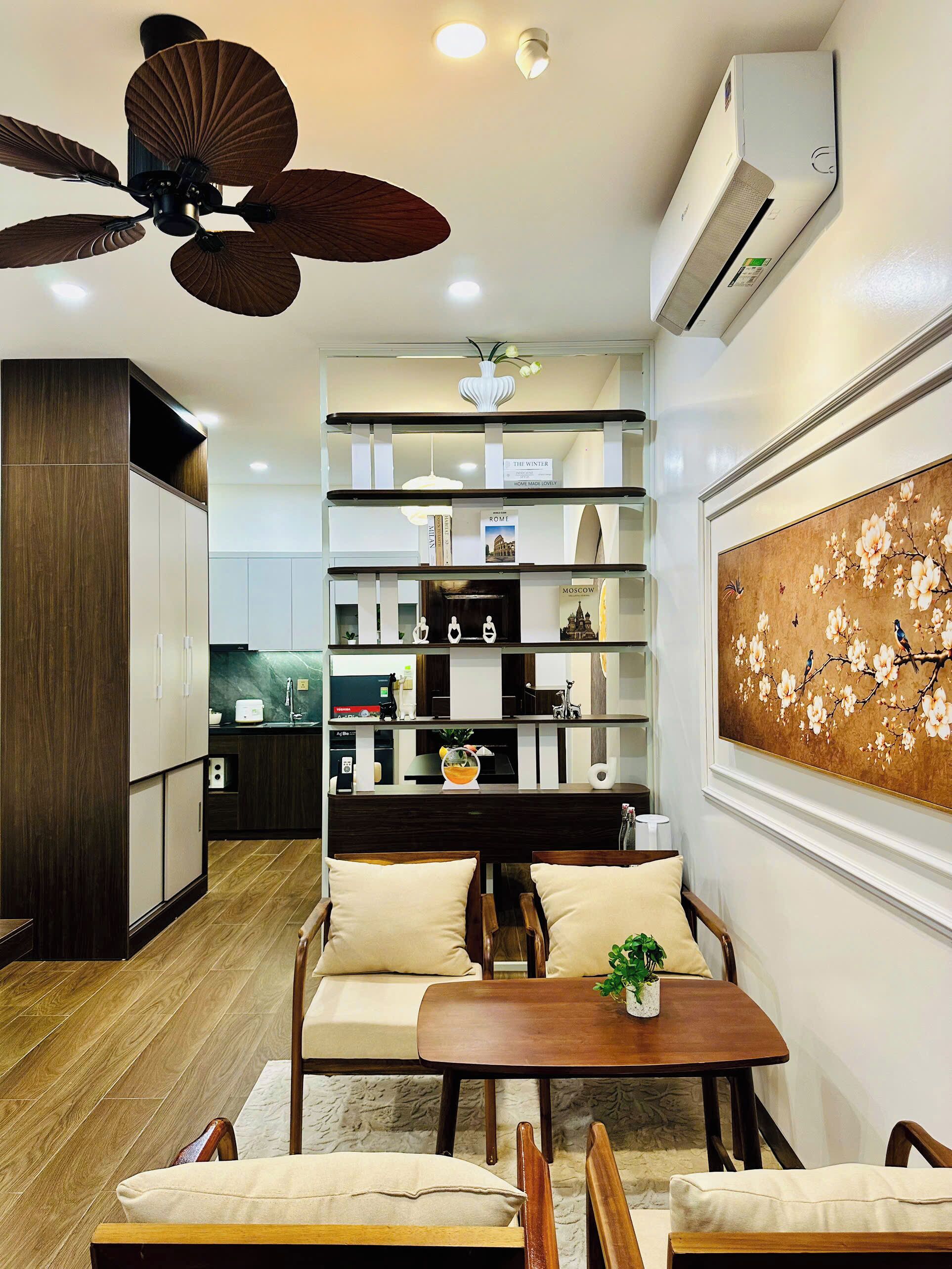 Una sala moderna con ventilador de techo, una mesa de comedor con sillas, un sofá y un elemento decorativo en la pared.