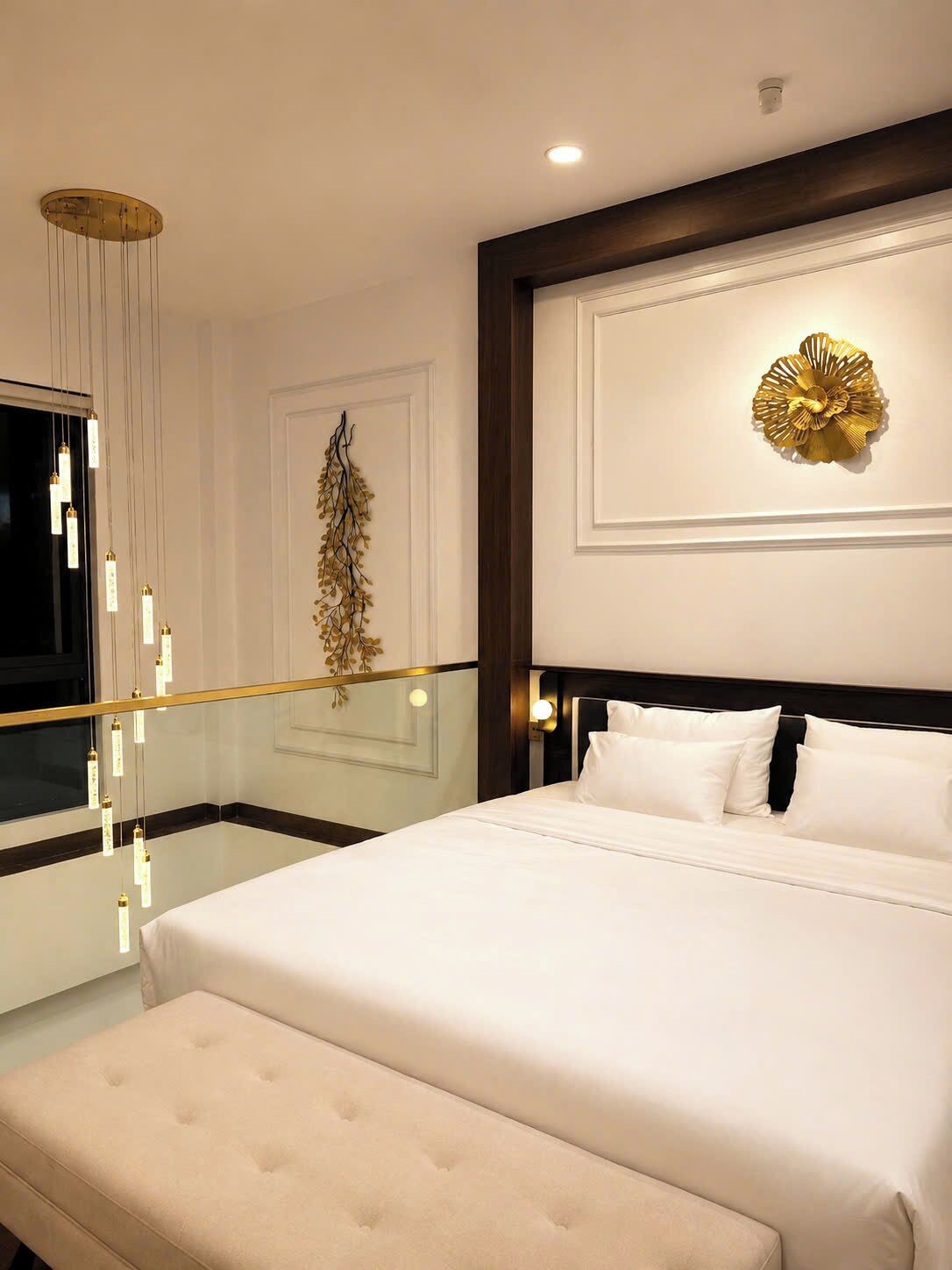 Une chambre d’hôtel avec un grand lit, un banc, un téléviseur fixé au mur et un élément décoratif mural.