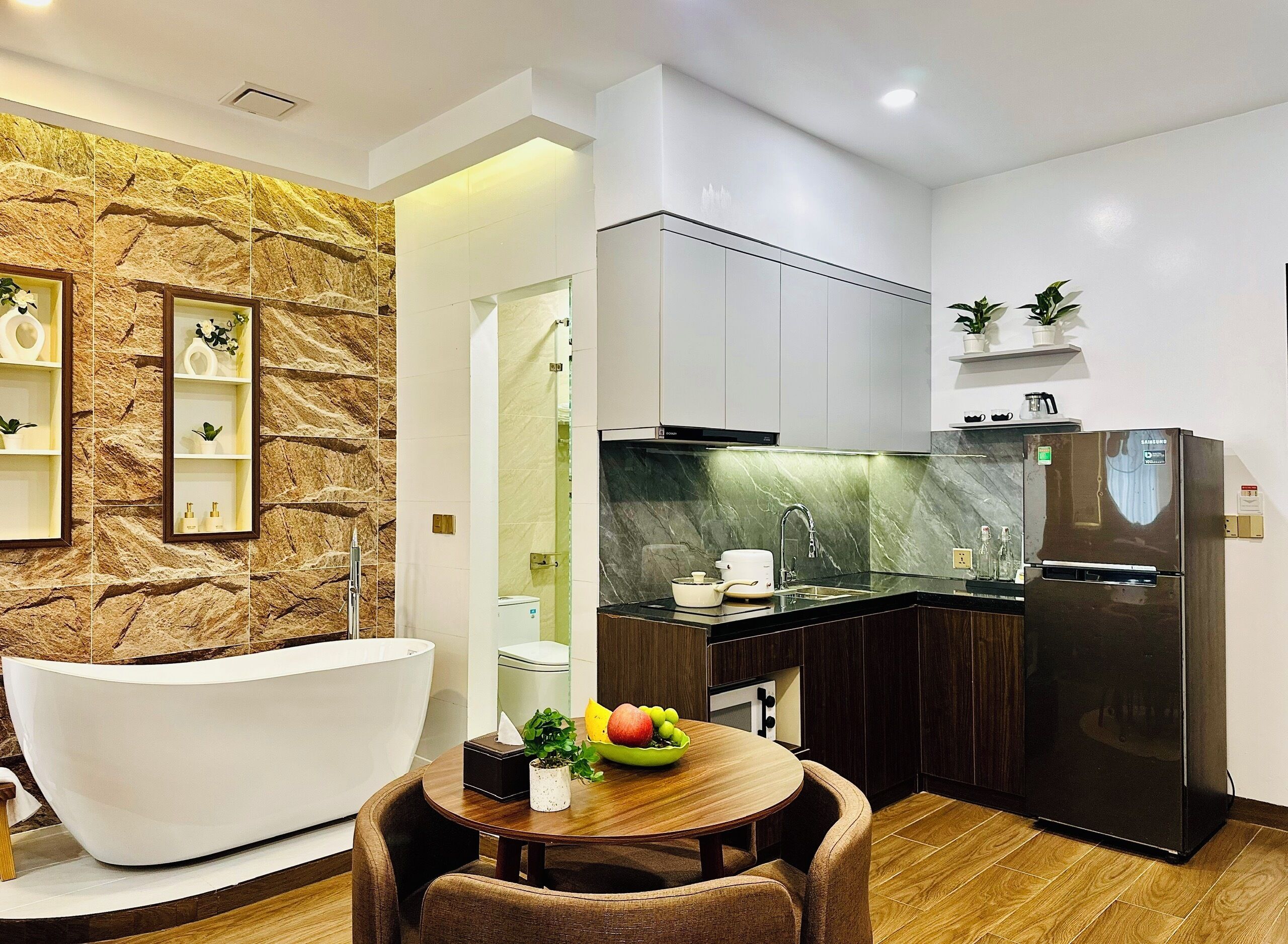 A modern kitchen with a built-in dishwasher, a black refrigerator, and a dining area with a round table and chairs.