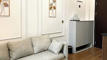 Una sala de estar moderna con un sofá gris, una mesa de centro blanca con una planta y un frutero, y obras de arte en las paredes.