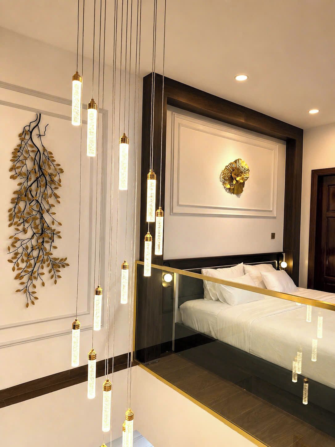 Una habitación de hotel moderna con una cama grande, un adorno mural y lámparas colgantes.