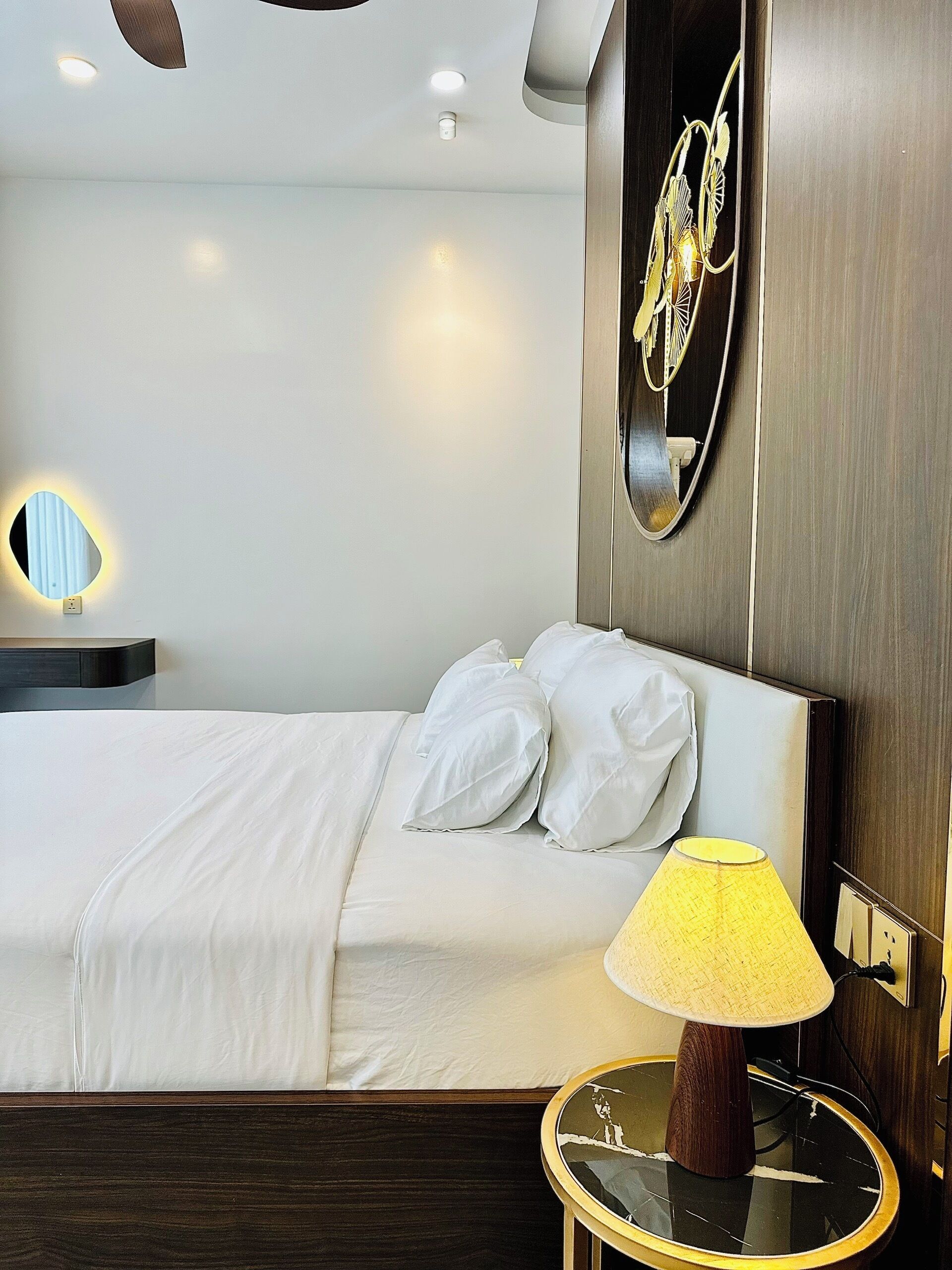 A hotel room with a bed, bedside lamp, and a wall-mounted mirror.