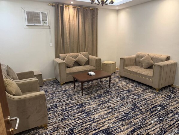 A living room with beige sofas, a coffee table, and a patterned rug.