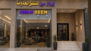 Una entrada de hotel con fachada de vidrio, un cartel que dice 'IWAN SEEN' y una escalera que conduce a la entrada.
