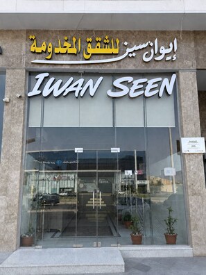 The exterior of a building with a large glass entrance and a sign that reads 'Iwan Seen'.