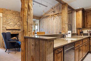 Une cuisine rustique avec un mur en pierre, des armoires en bois et un grand miroir.