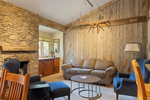 Ein gemütliches Wohnzimmer mit Steinwand, Holzvertäfelung, Kamin, einer Couch und einem Couchtisch.