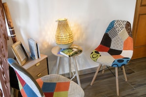 A room with a wooden chair, a table with books, and a lamp.