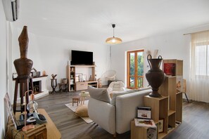 A modern living room with a sofa, a television, and a large vase.