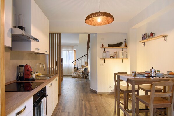A modern kitchen with wooden countertops, a dining area with a wooden table and chairs, and a staircase leading to another level.