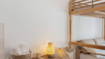 Ein Stockbett mit Holzrahmen, eine Nachttischlampe, eine Taschentuchbox und ein Korb mit Handtüchern.