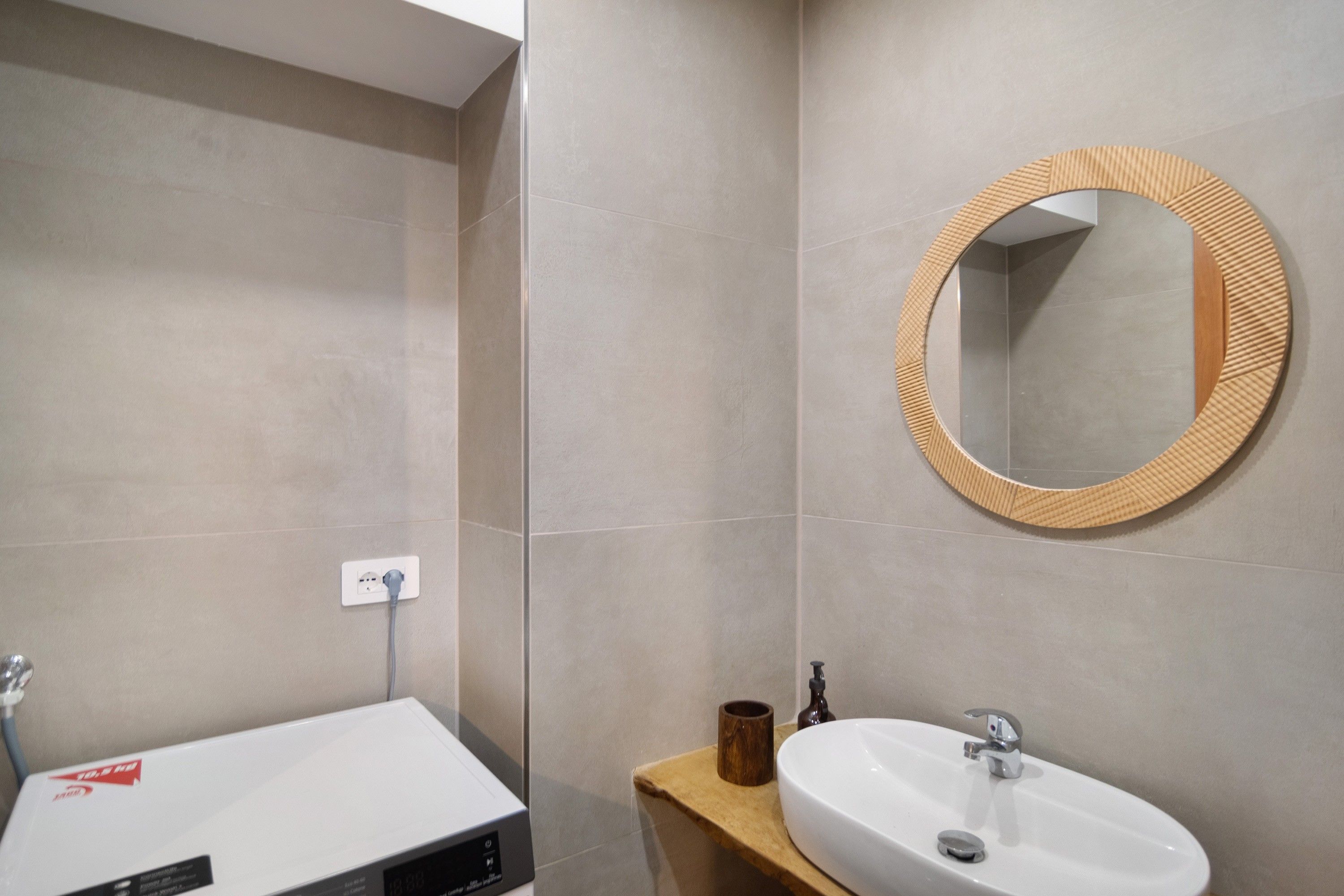 Un baño con un lavamanos blanco, un espejo con marco de madera y un mueble de tocador de madera.