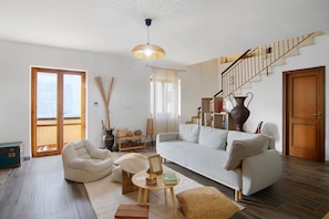 A living room with a sofa, armchair, coffee table, and a staircase.