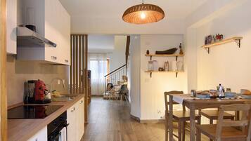 A modern kitchen with wooden countertops, a dining area with a wooden table and chairs, and a staircase leading to another level.