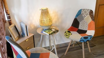 Une pièce avec une chaise en bois, une table avec des livres et une lampe.