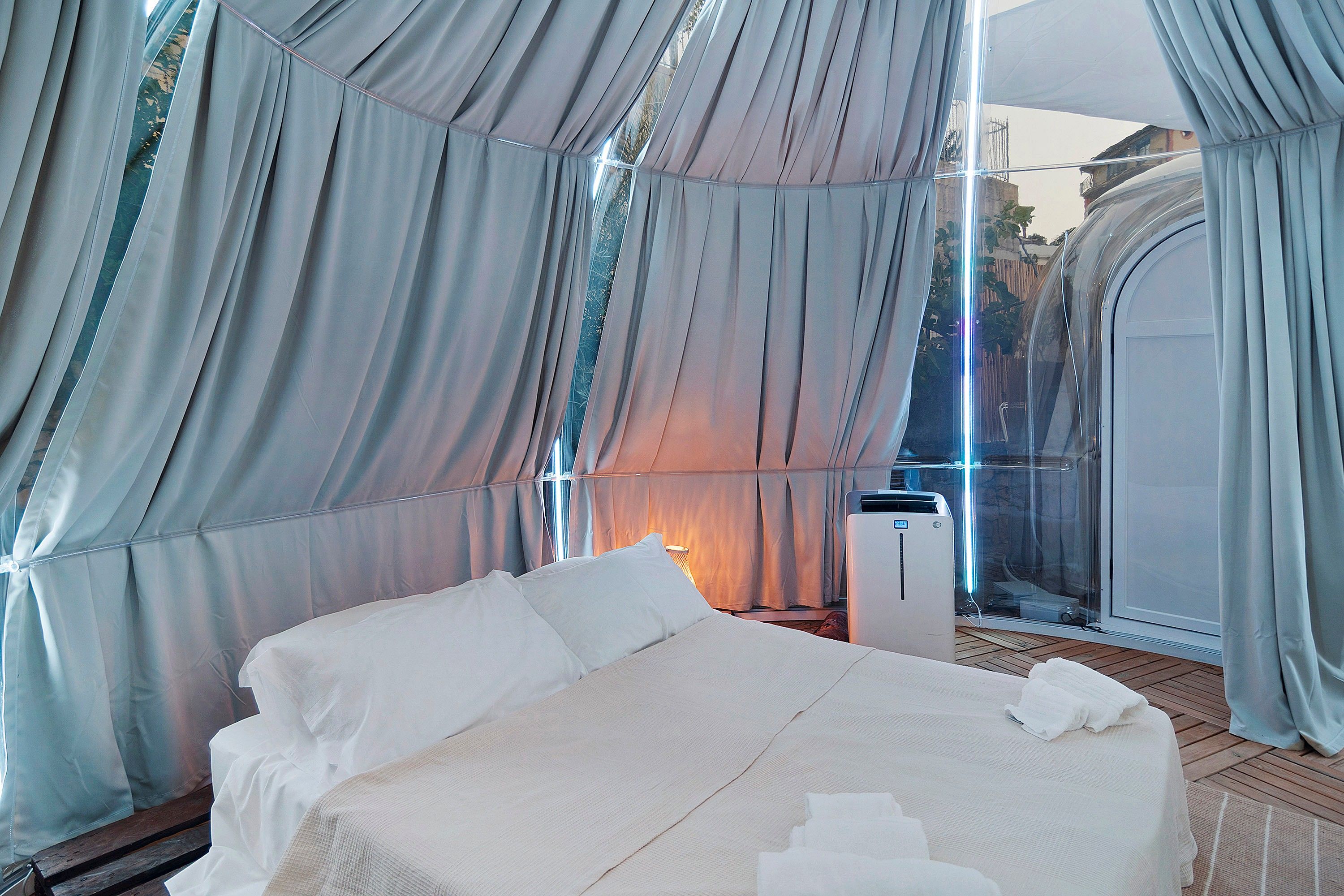 A tent-style room with a bed, a heater, and a window.