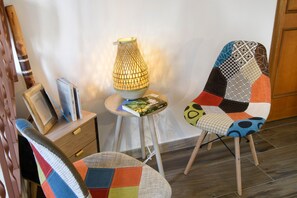Una habitación con una silla de madera, una mesa con libros y una lámpara.